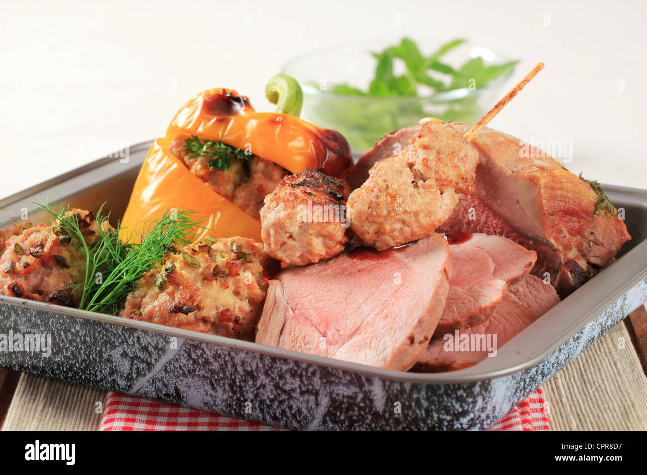 Roast pork, stuffed pepper and tomatoes and kebabs in a baking pan Stock Photo