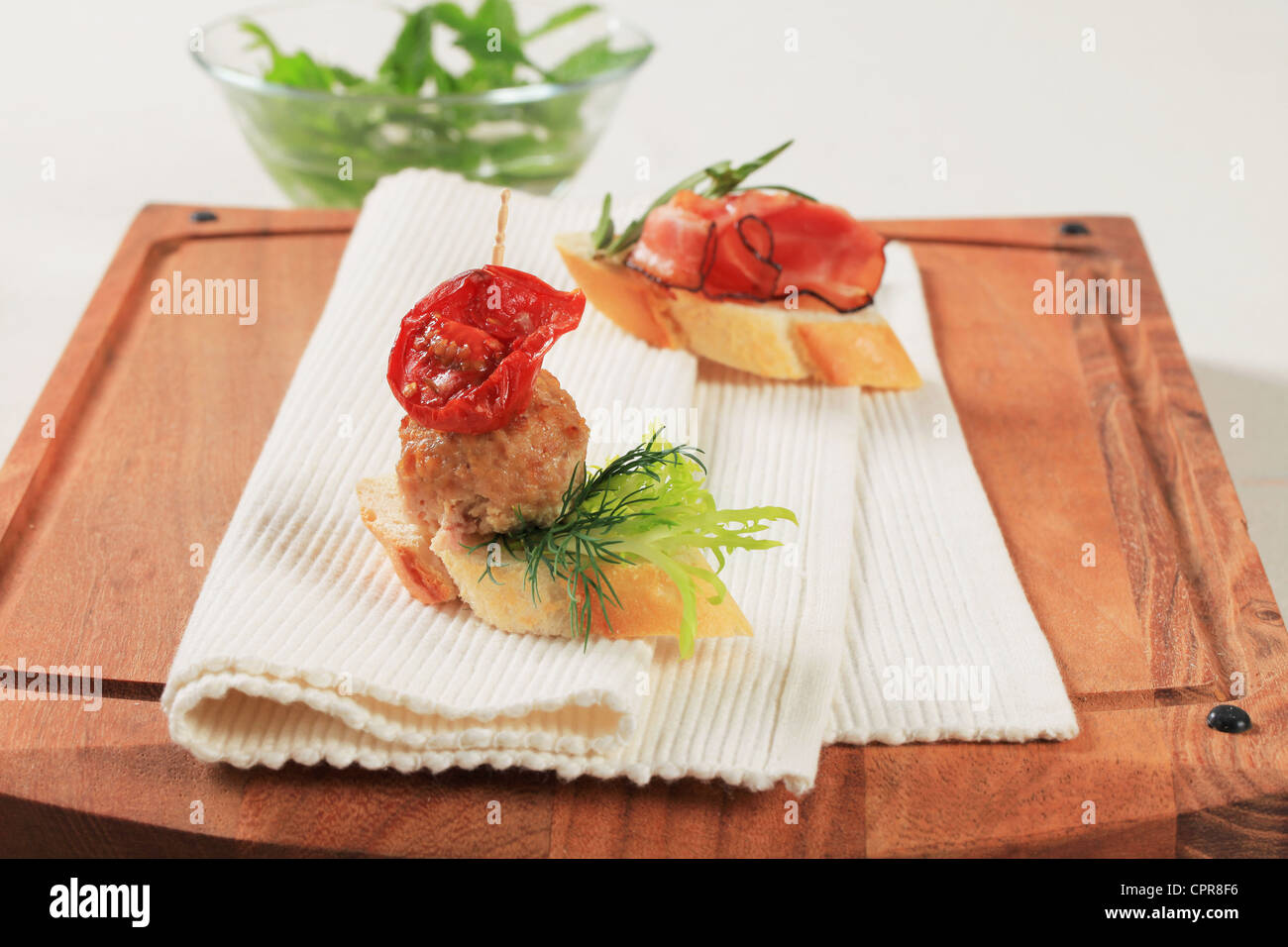 Meatball and prosciutto canapes on a cutting board Stock Photo