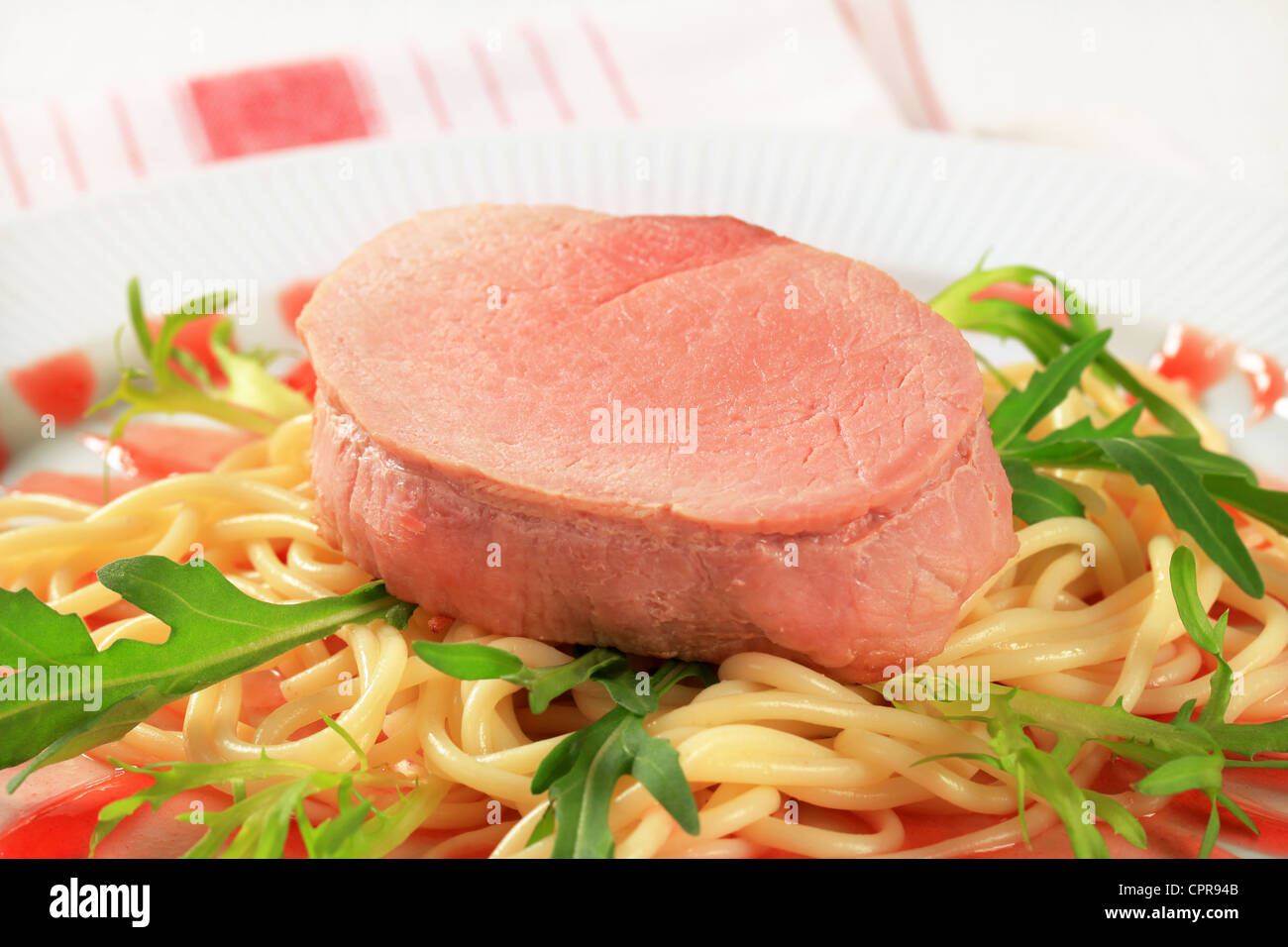 Pork fillet and spaghetti with raspberry balsamic reduction and rocket Stock Photo