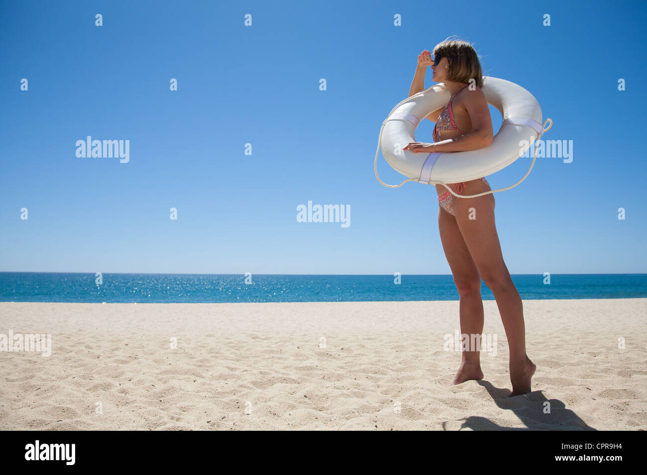 Young woman watching the bay with a white life buoy Stock Photo