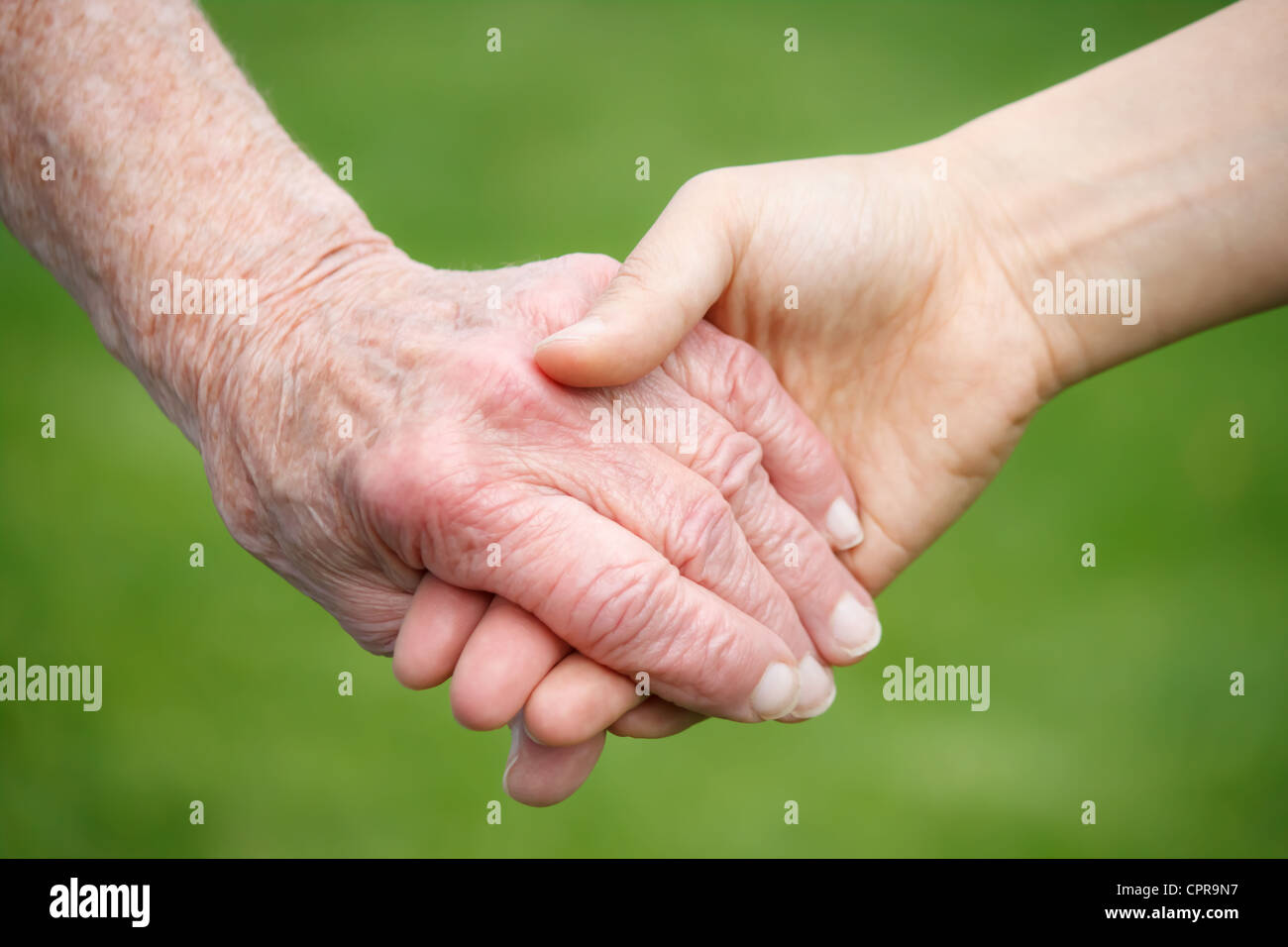 Senior lady and young woman holding hands Stock Photo