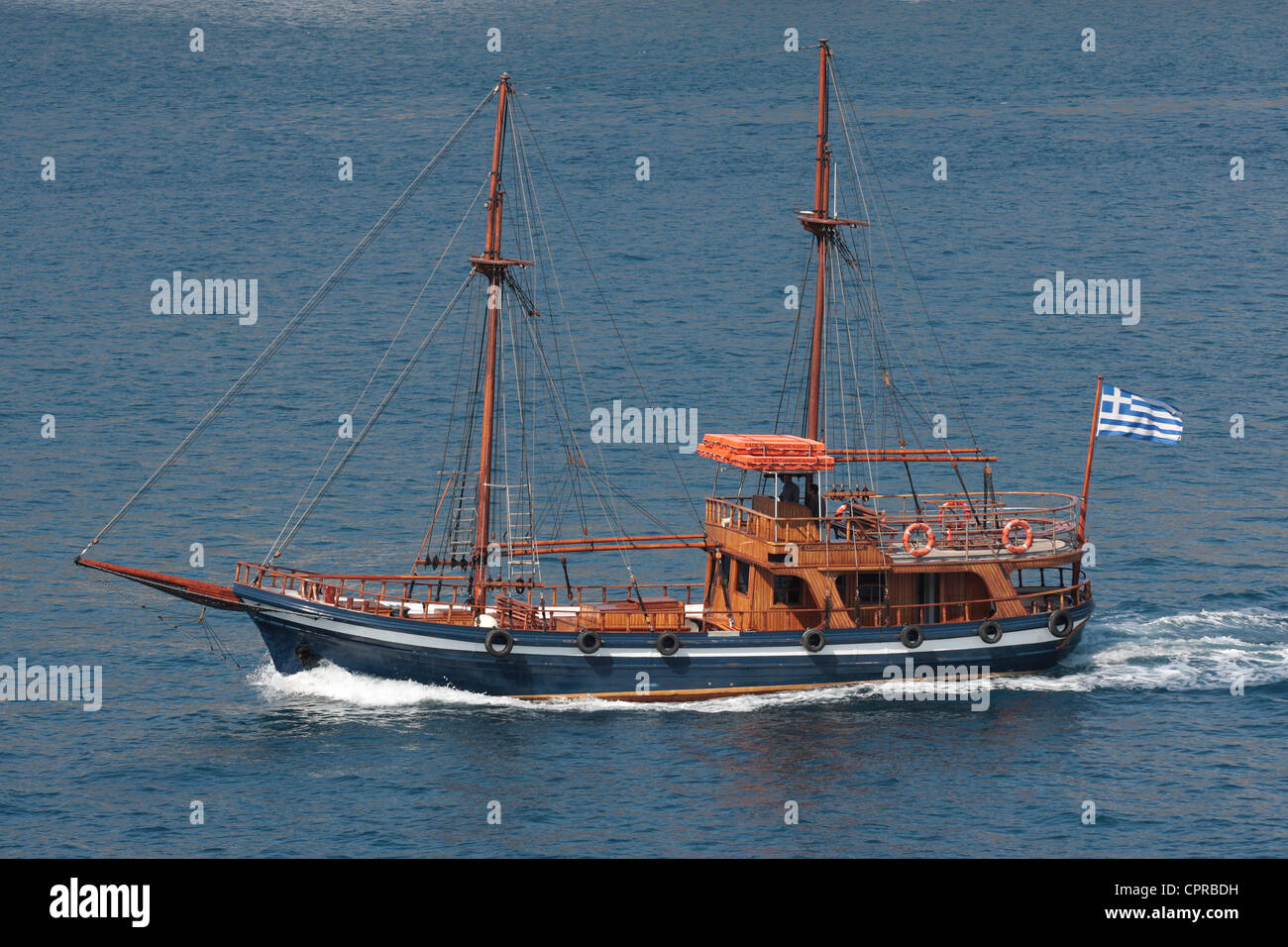 A tourist boat, rigged as a schooner but without sails, under power in the Santorini caldera Stock Photo