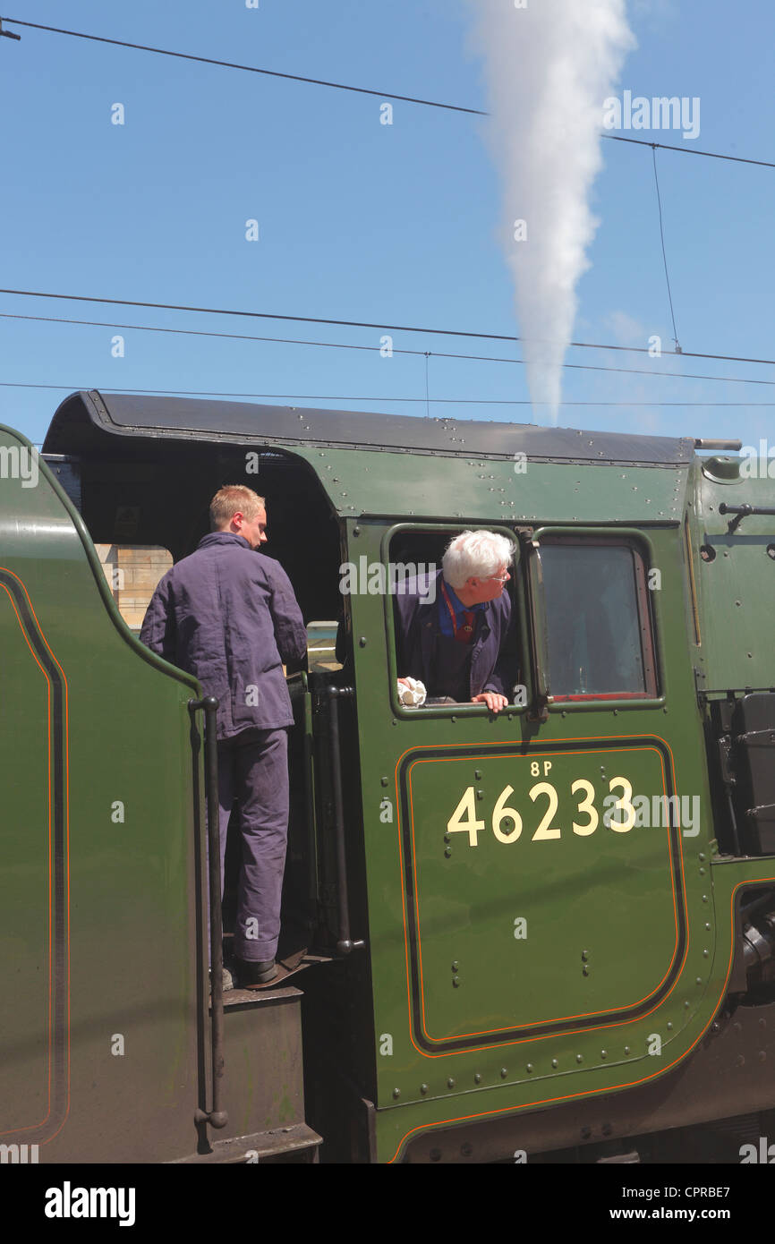 Driver and Fireman on LMS Princess Coronation Class 6233 Duchess of Sutherland steam train at Carlisle Railway Station, Stock Photo