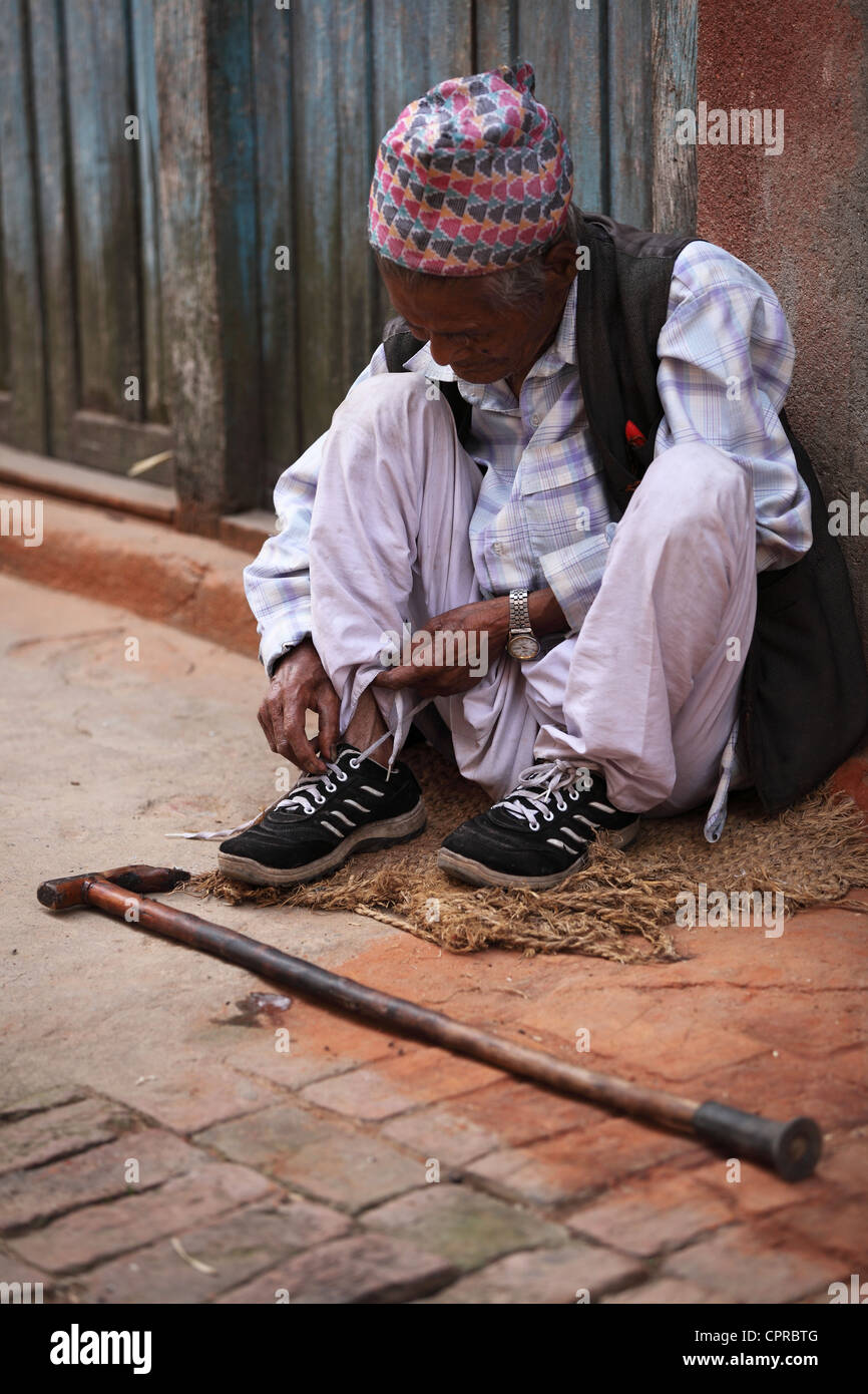 Old Nepali man doing his shoe laces Stock Photo