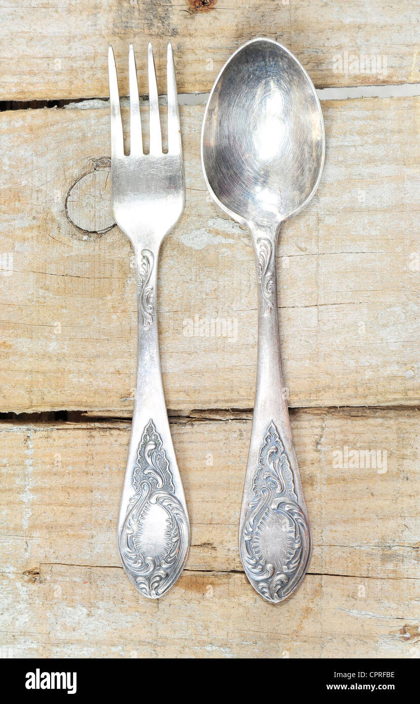 Vintage silver fork and spoon with ornaments on wooden background Stock Photo