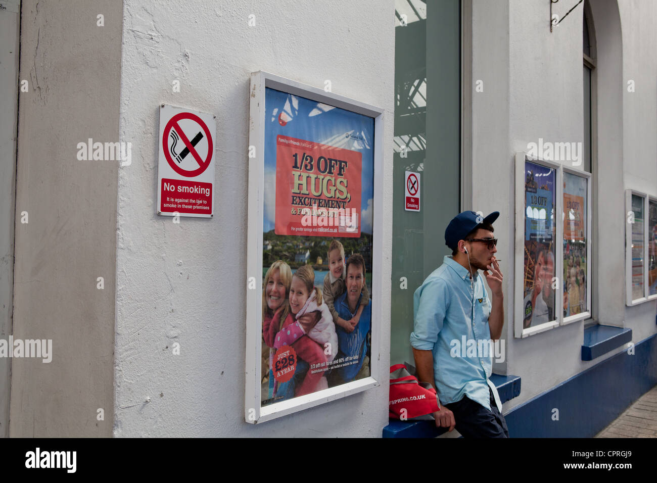 Man smoking next to a no smoking sign Stock Photo