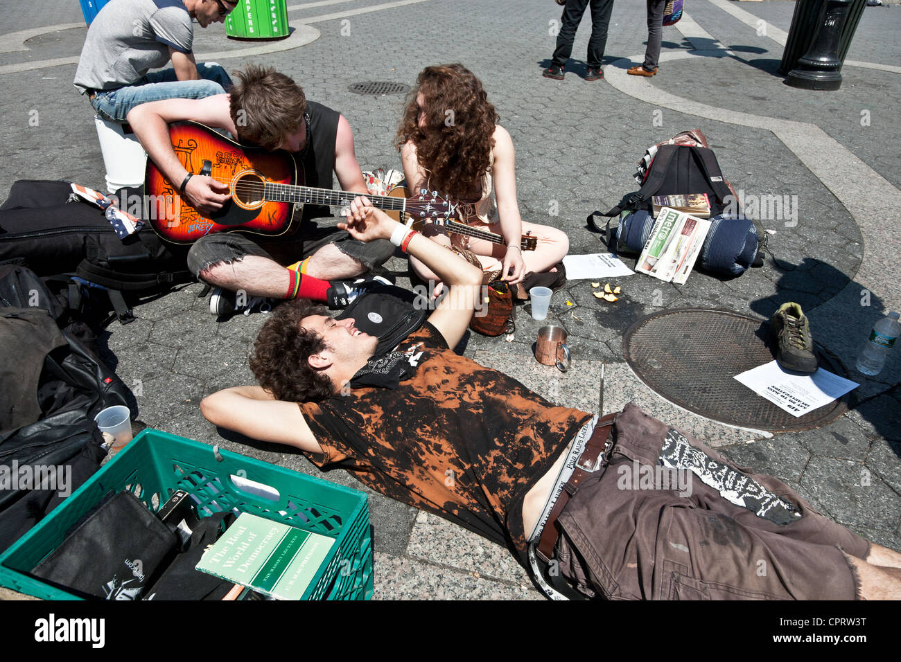 group of happy Occupy Wall Street young people relax with musical instruments on  sunny spring day in Union Square New York City Stock Photo