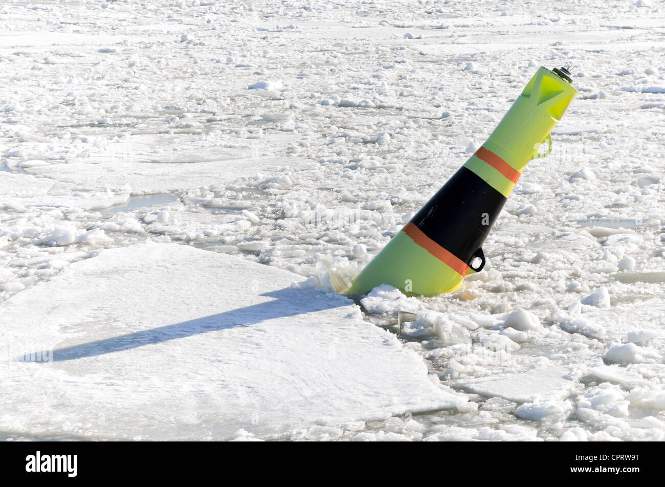Conical black and yellow buoy on frozen Baltic sea Stock Photo