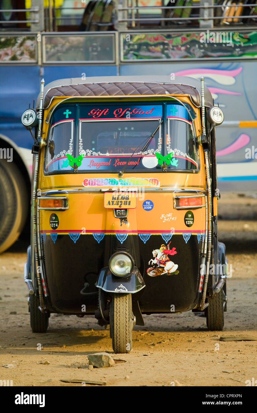 black and yellow Auto rickshaw head on  in front of a bus in India Stock Photo