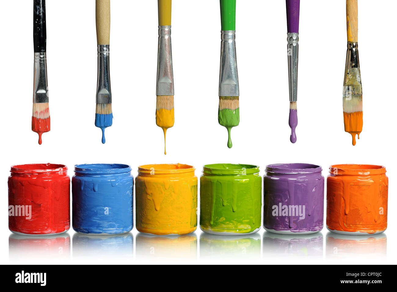 Paintbrushes dripping paint of various colors into containers Stock Photo
