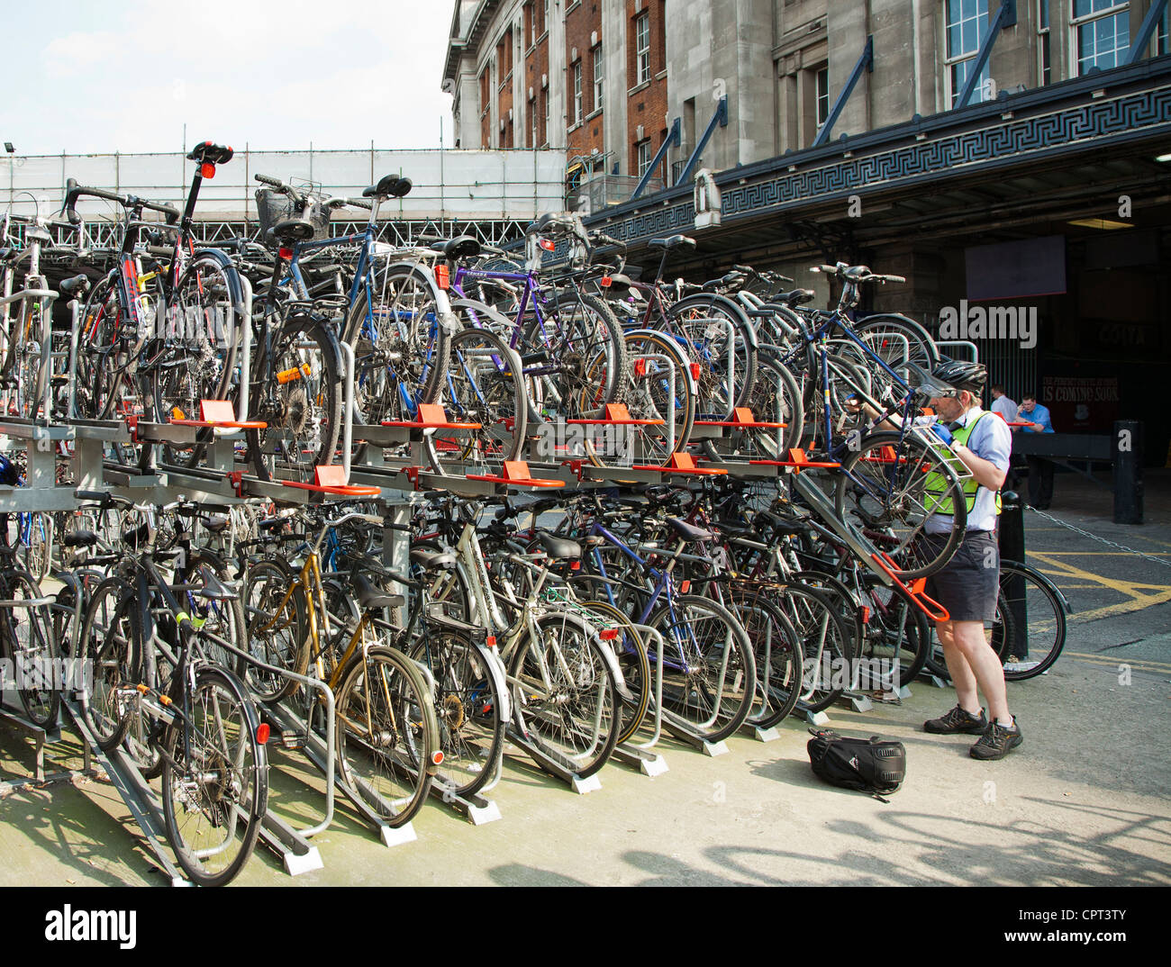A man parking his bike on a raised rack outside Waterloo station in