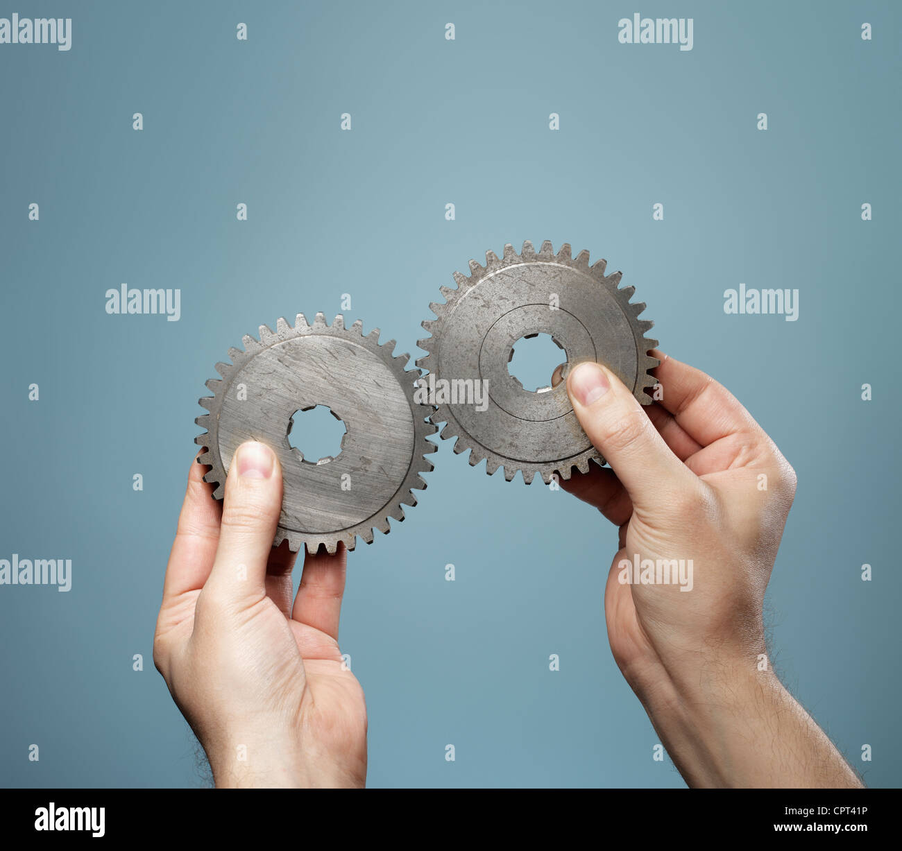 A Man holding a matching pair of old cog gear wheels in his hands. Stock Photo