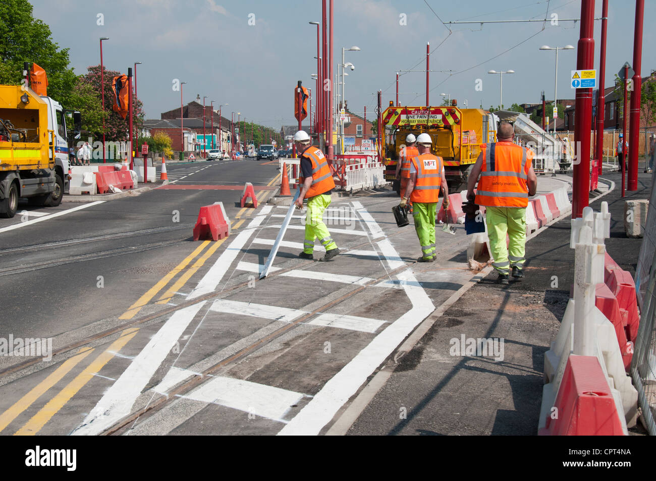 Workmen marking a road surface next to a new Metrolink tram stop.  Manchester Rd, Droylsden, Manchester, England, UK Stock Photo