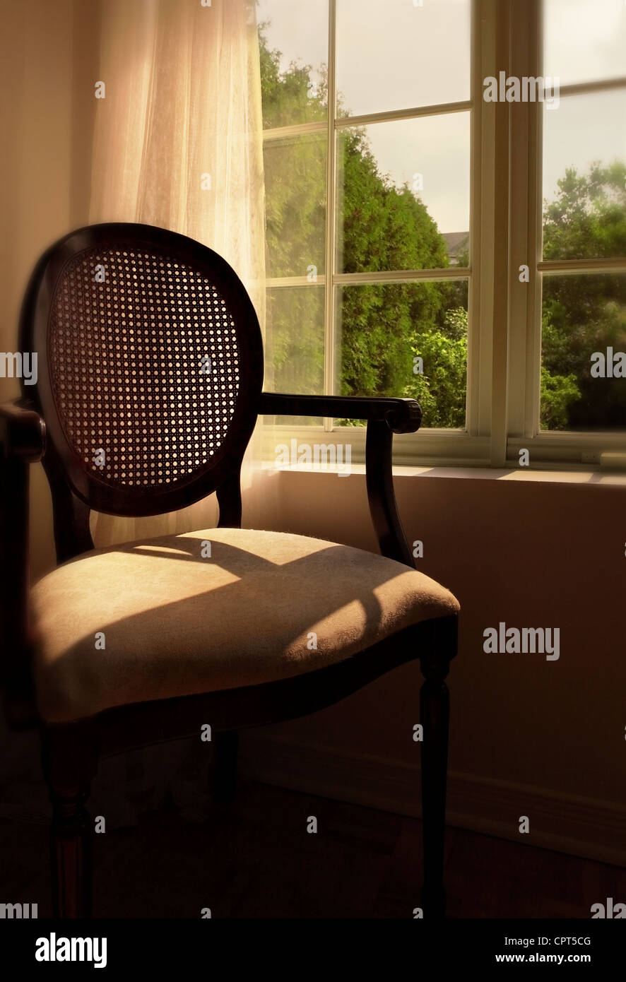 An empty chair in front of a window with sunlight streaming in Stock ...