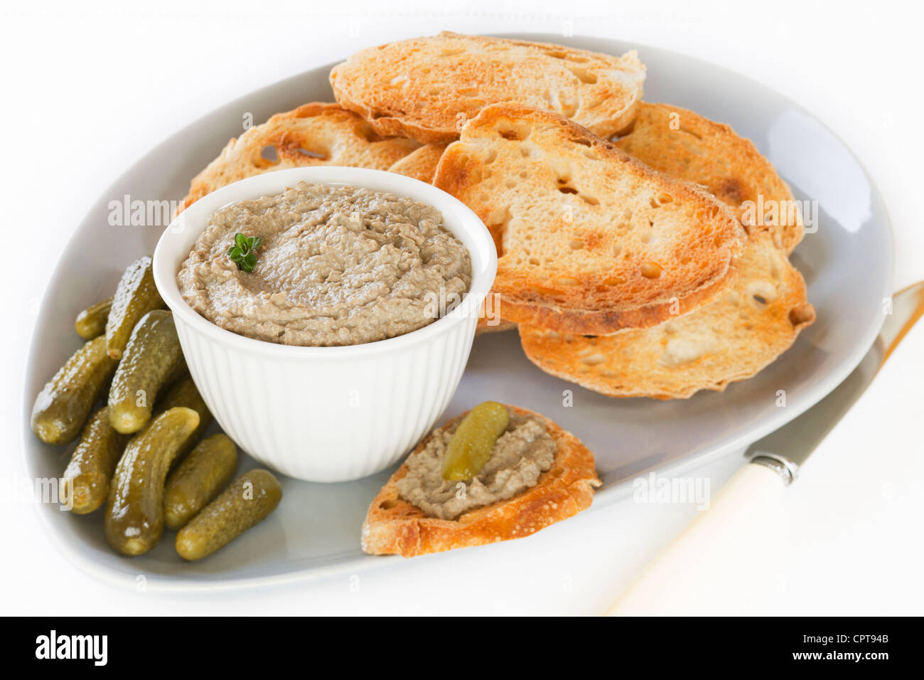 Home made chicken liver pate with with toasted sourdough and gherkins, arranged on a platter. Stock Photo