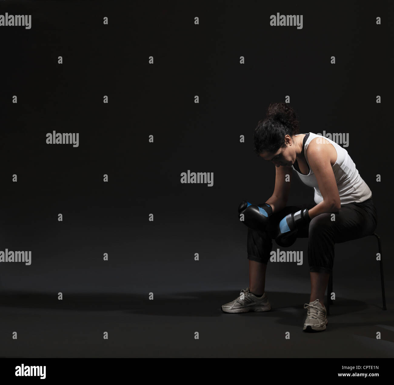 Female boxer sitting against black background Stock Photo
