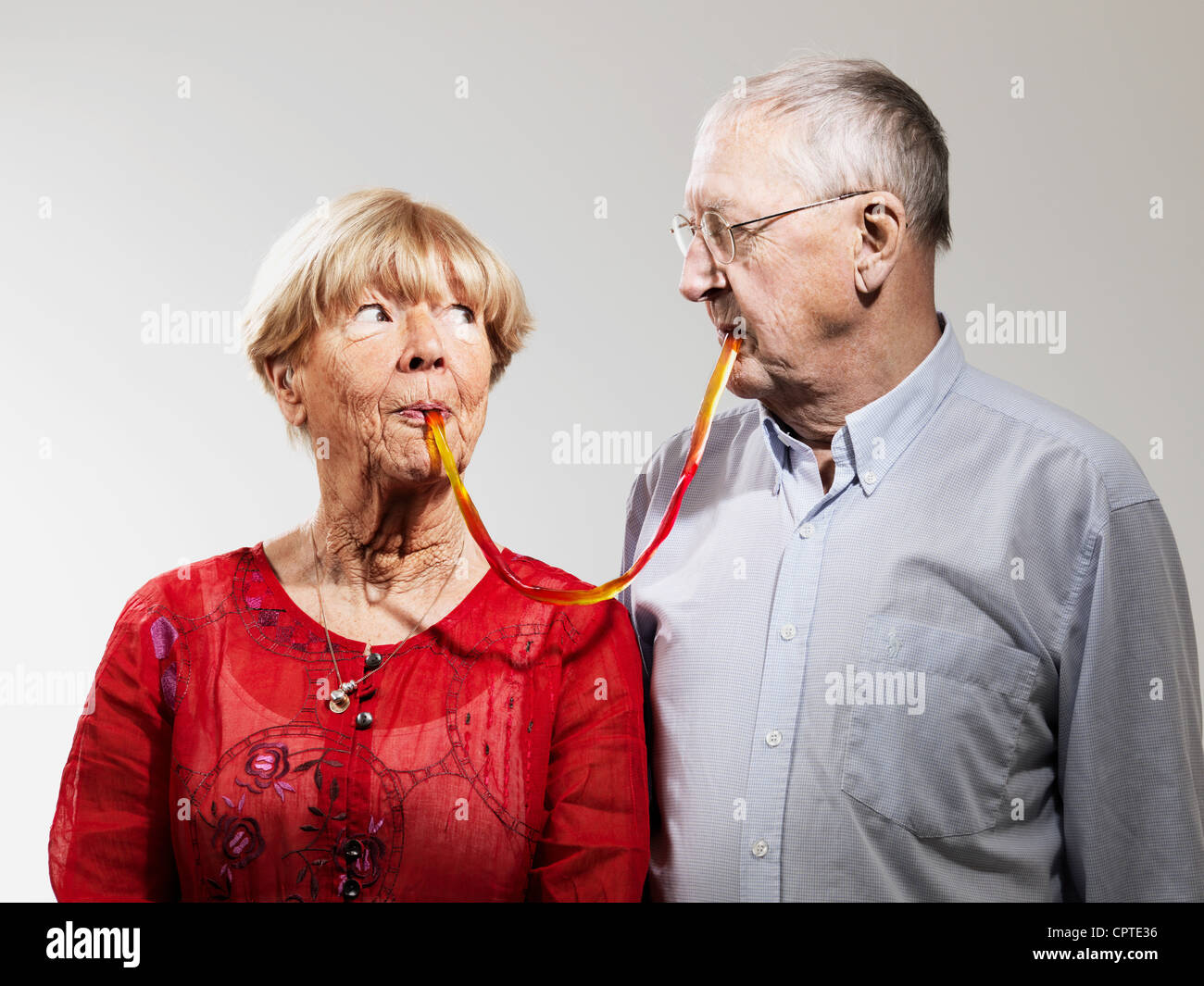 Senior couple sharing confectionery against white background Stock Photo