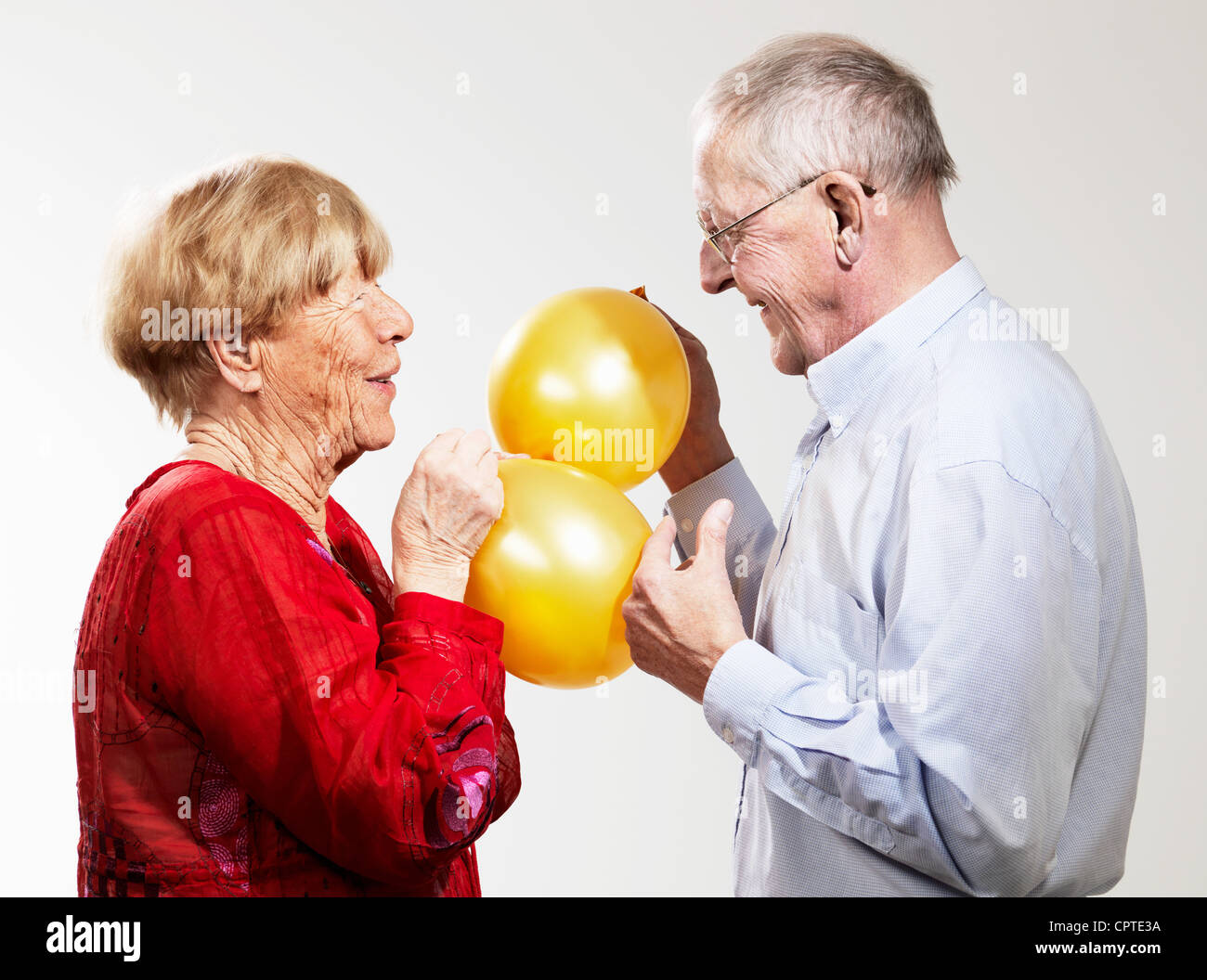 Senior holding balloons against white background Stock Photo
