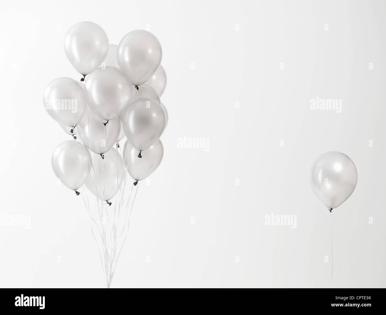 Silver balloons floating against white background Stock Photo