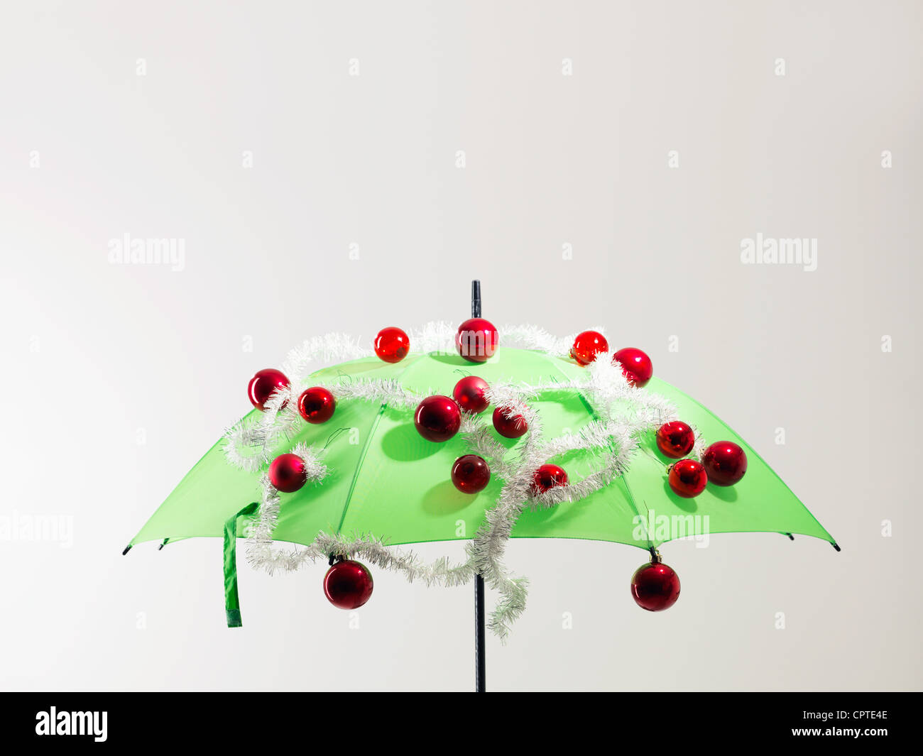 Green umbrella with Christmas decorations against white background