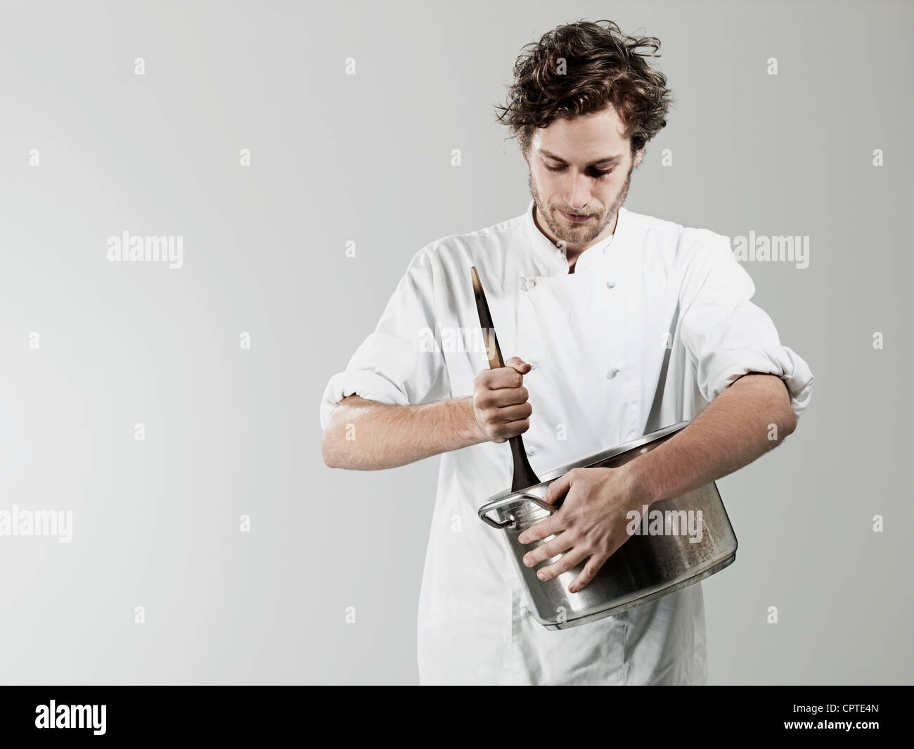 Chef stirring in pan against white background Stock Photo