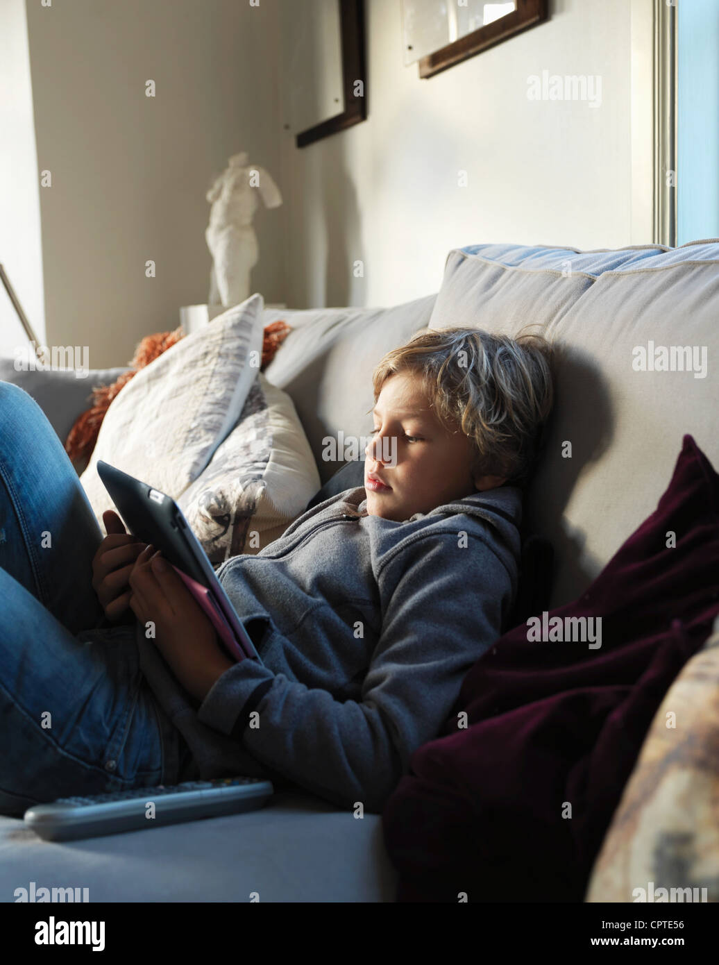 Teenage boy relaxing on sofa and using digital tablet Stock Photo