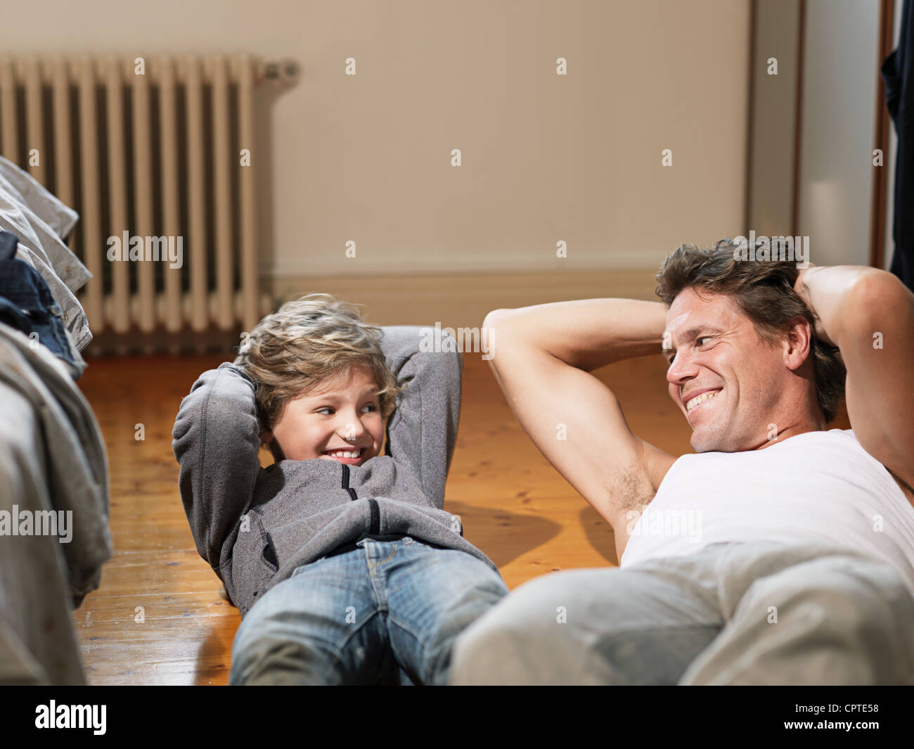 Mature man and son performing exercises in bedroom Stock Photo