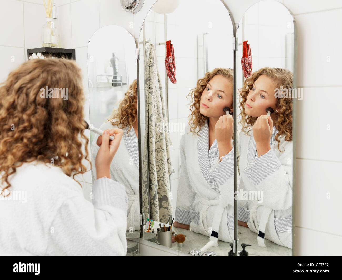 Young woman applying make-up in mirror Stock Photo