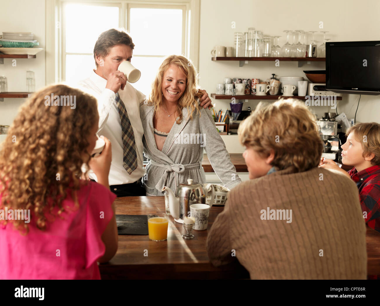 Family sitting together at kitchen table over breakfast Stock Photo - Alamy
