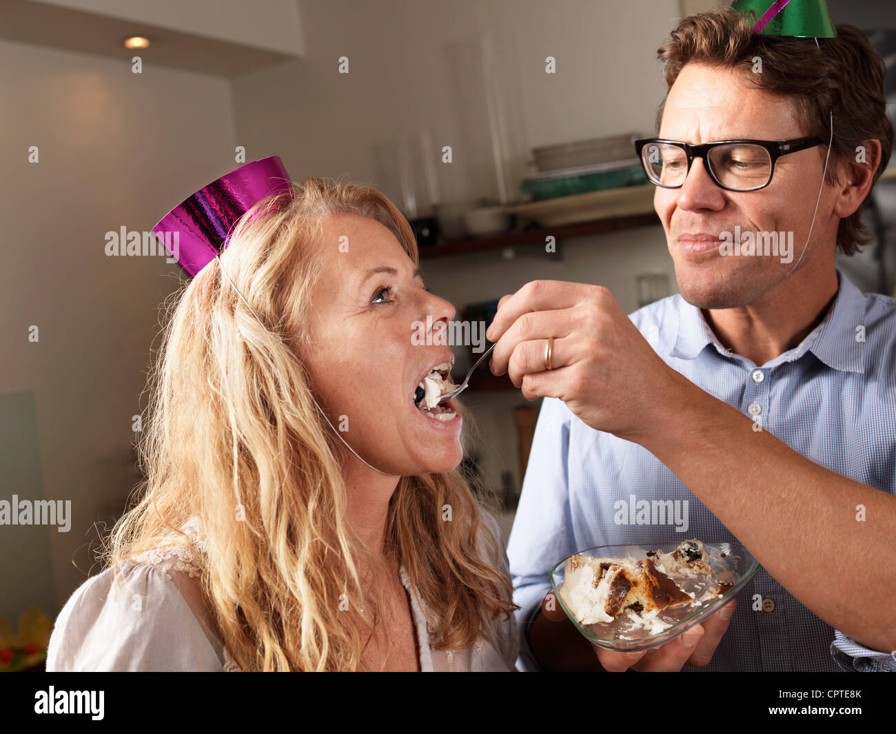 Mature man feeding cake to wife Stock Photo