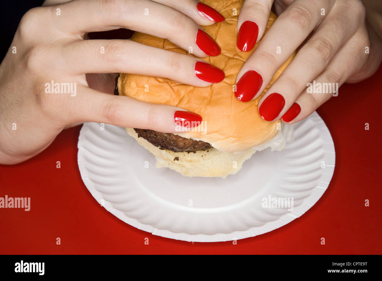 Woman with red fingernails holding burger Stock Photo