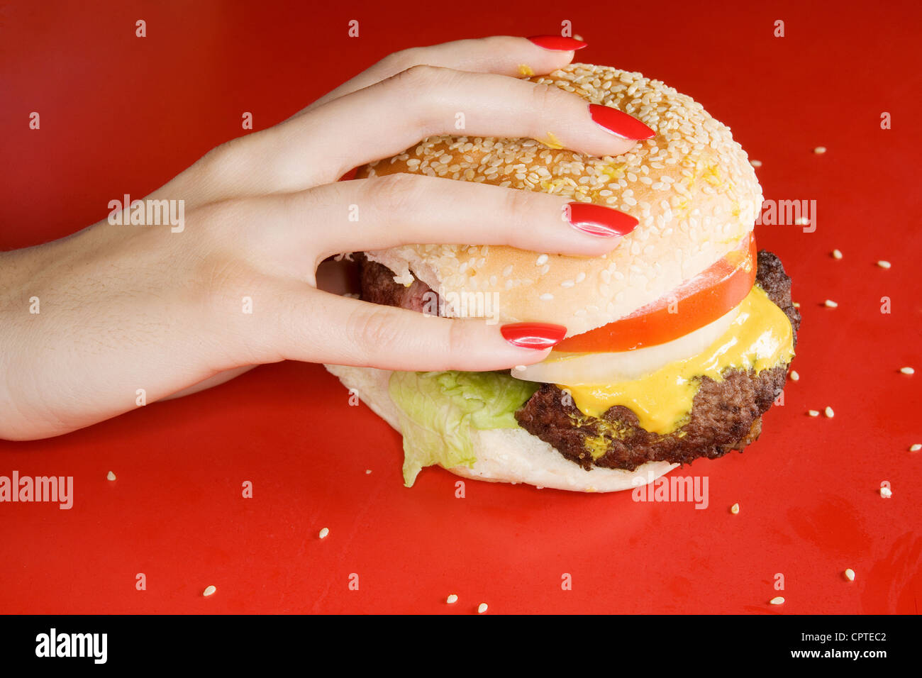 Woman with red fingernails holding burger Stock Photo