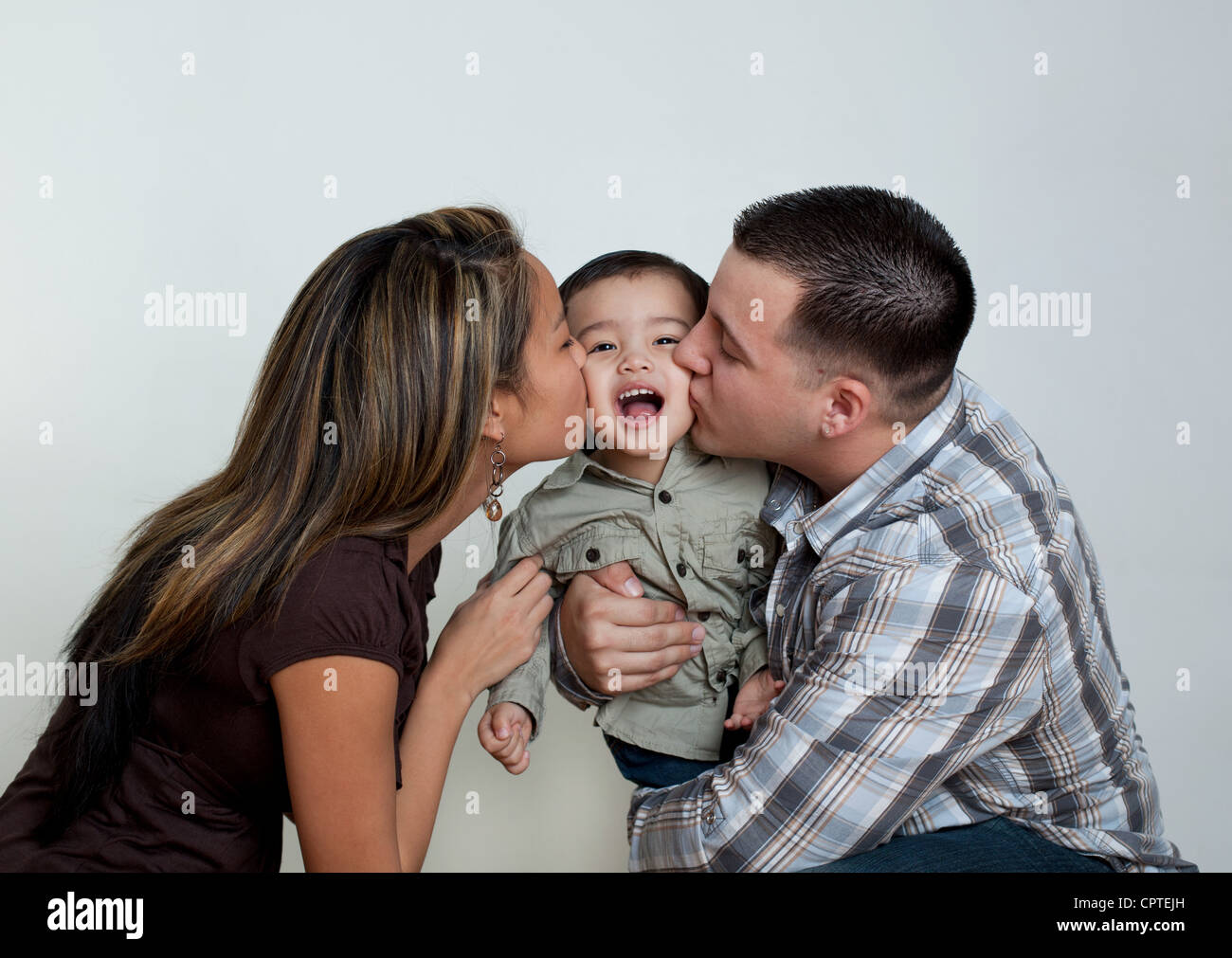 Mother and father kissing toddler son Stock Photo
