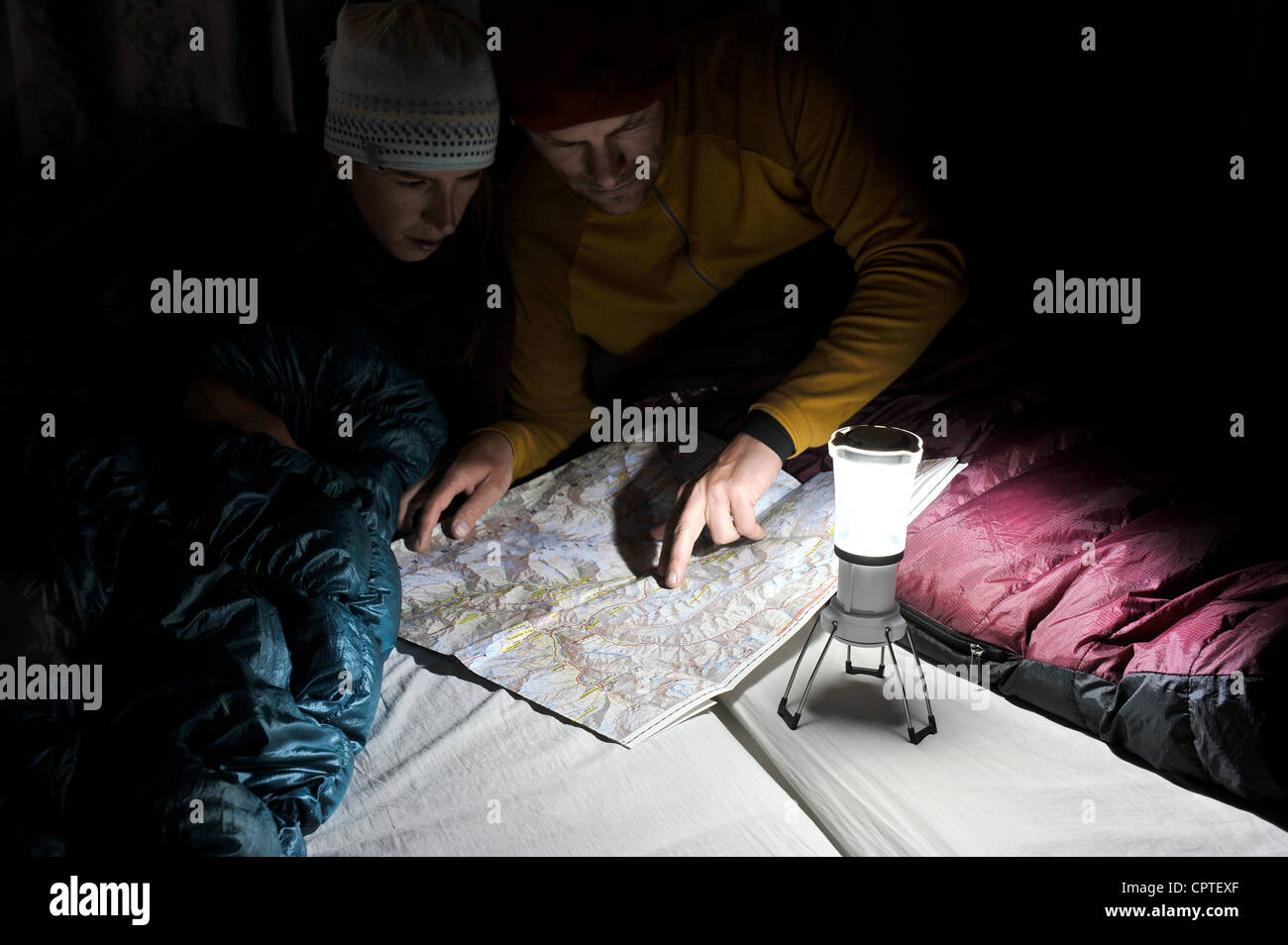 Couple in sleeping bags, looking at trail map, Yak Kharka, Nepal Stock Photo