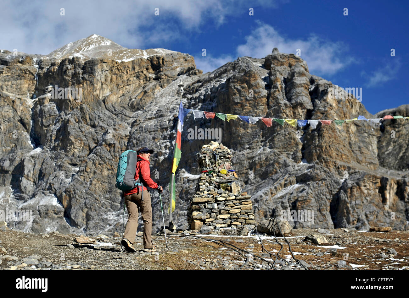 Female trekker near prayer flags, Thorung La, Nepal Stock Photo