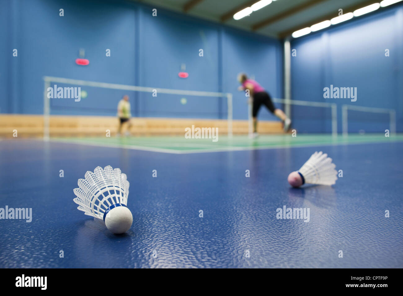 badminton badminton courts with players competing; shuttlecocks in