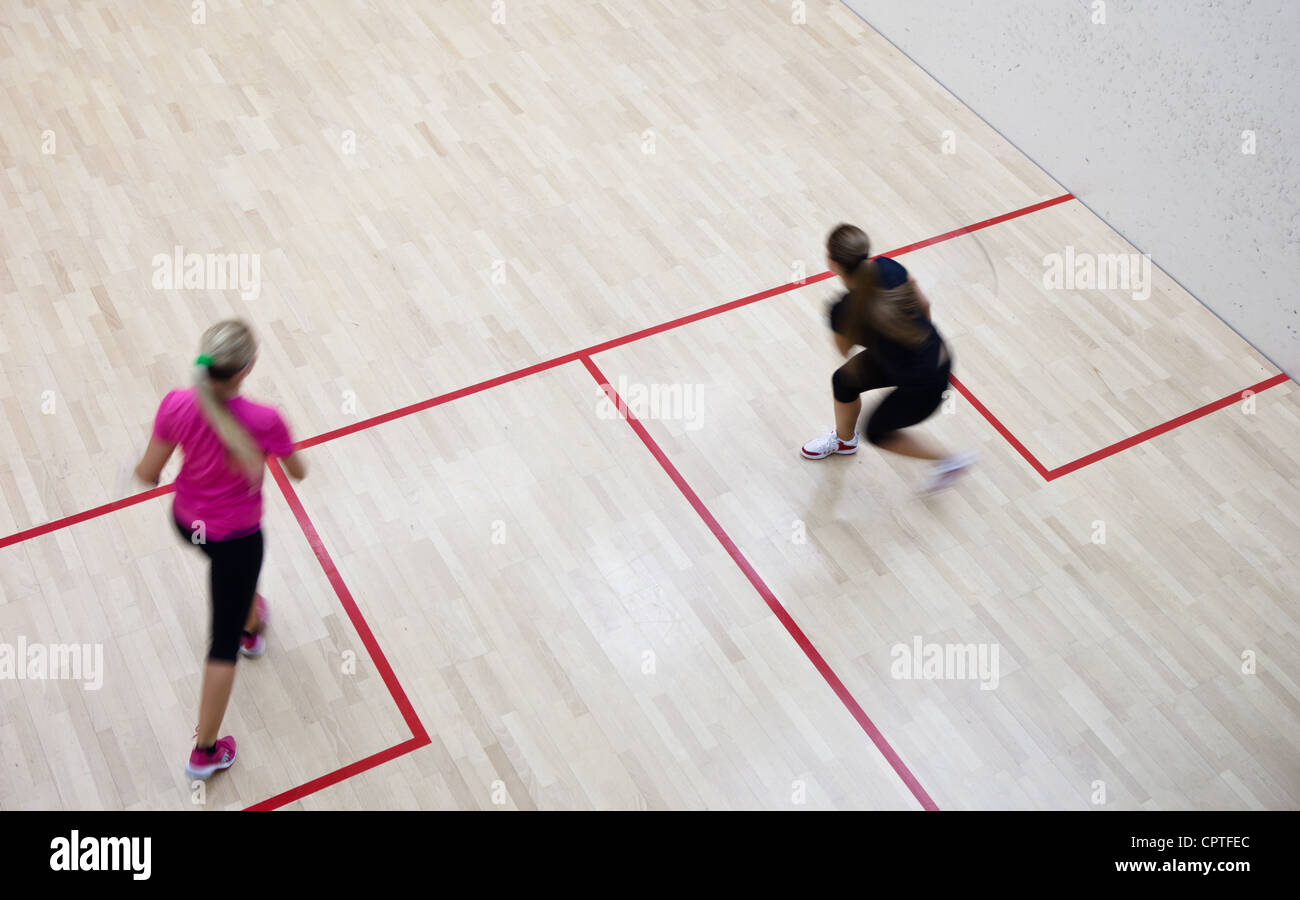 Two female squash players in fast action on a squash court (motion