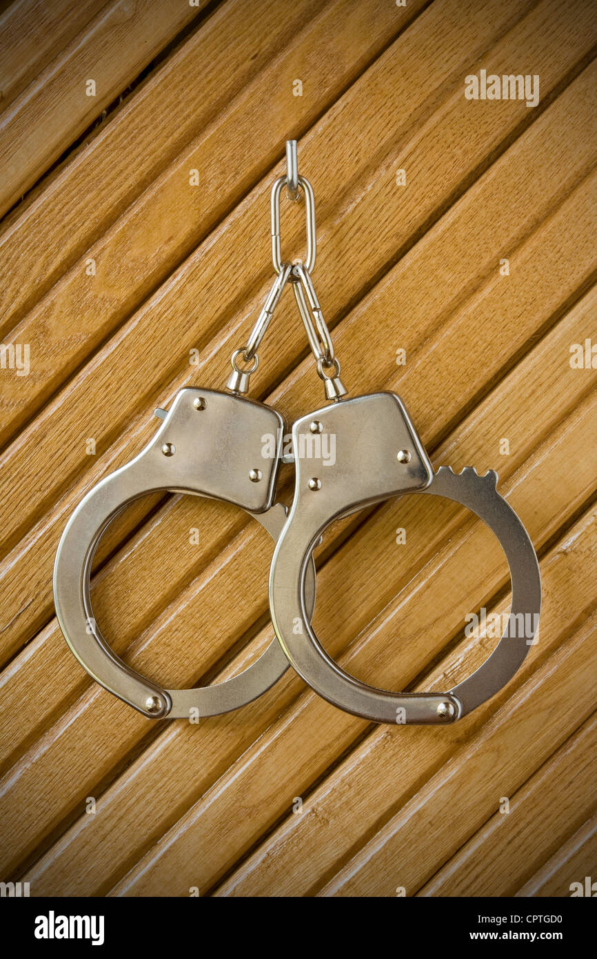 metal handcuffs hanging on the wooden wall Stock Photo