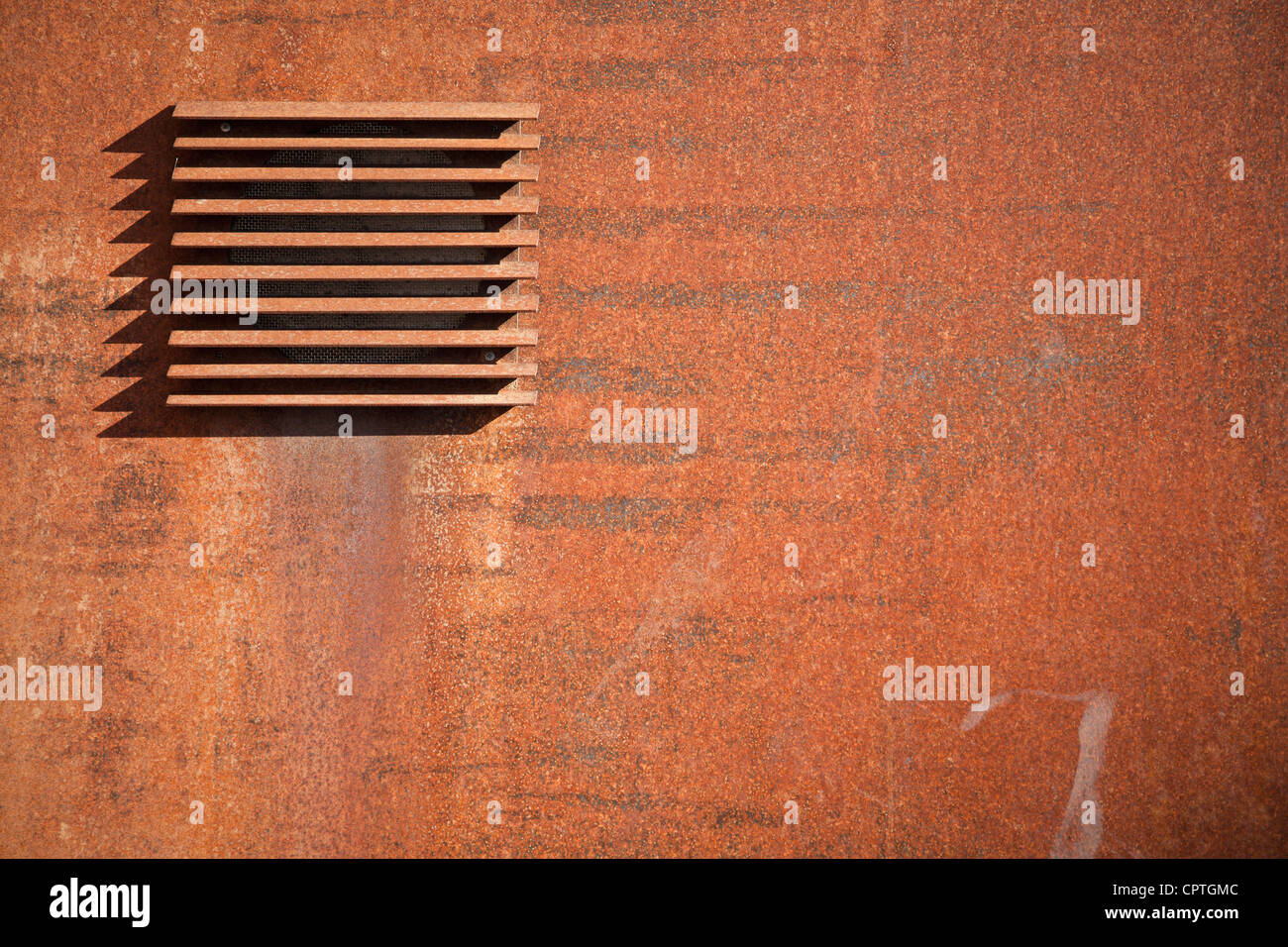 Fragment of a metal rusted wall with ventilation grille Stock Photo