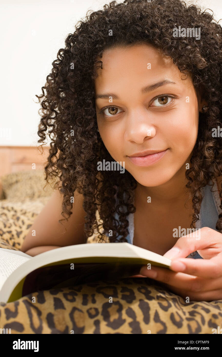Young woman lying on her bed reading a book Stock Photo Alamy