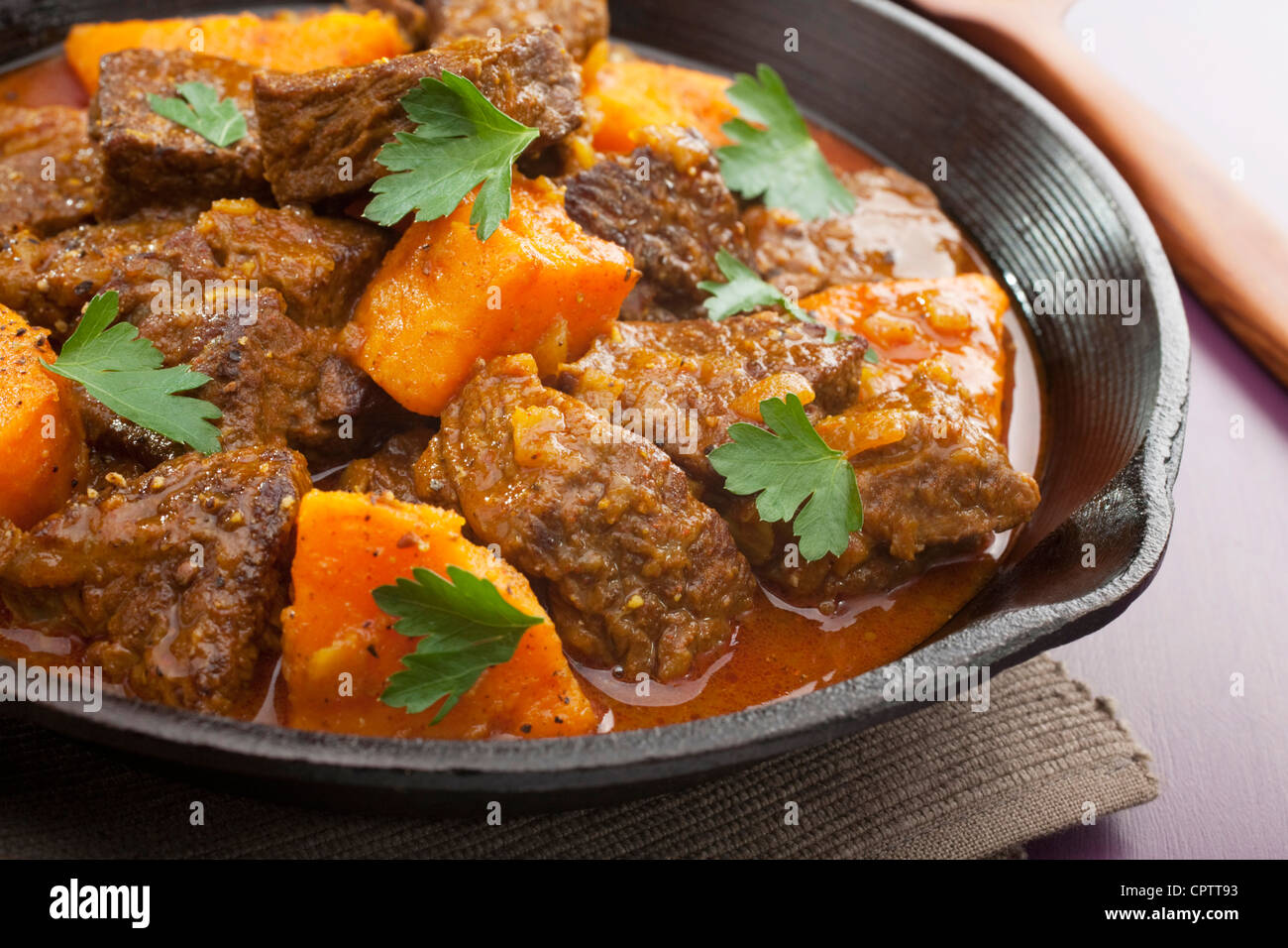 Moroccan tagine or stew of beef with sweet potato, in a cast iron pan. Stock Photo