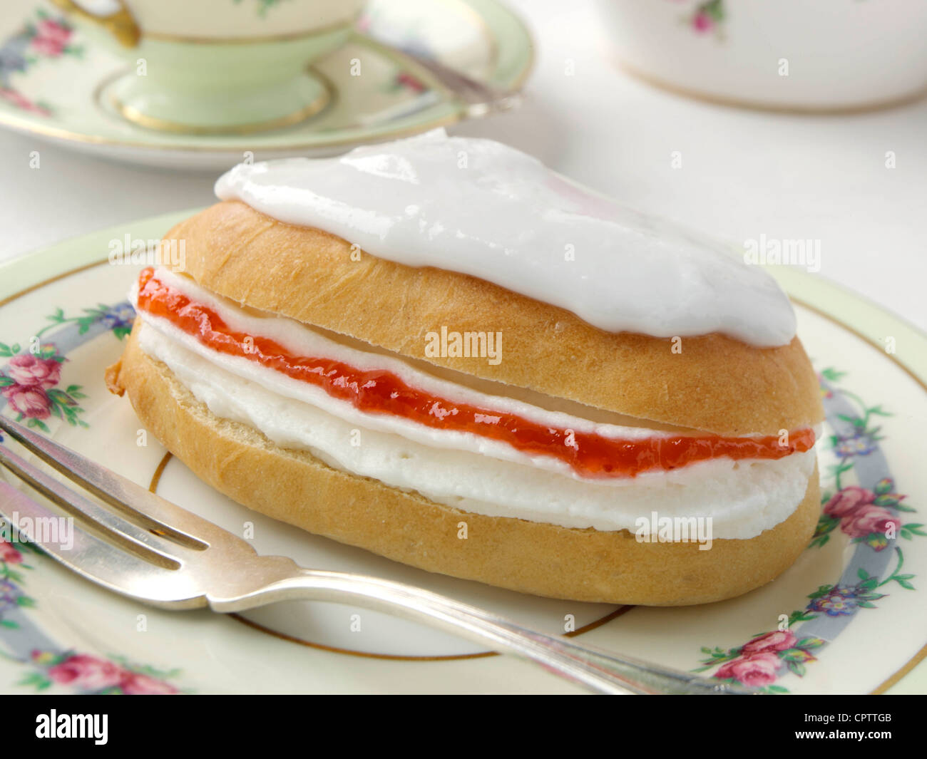 Individual strawberry jam cream filled iced finger bun hires stock