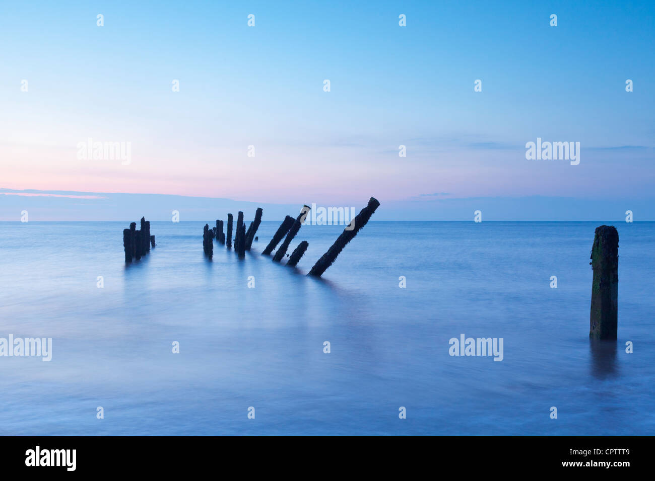 Old sea defences at dawn, smooth water from long exposure. Stock Photo