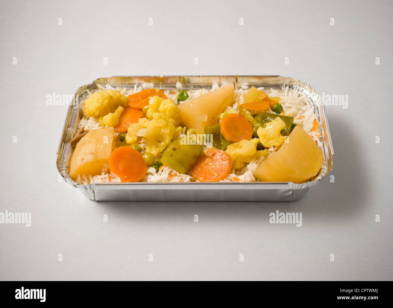 Rice with vegetables in a foil box takeaway. Stock Photo