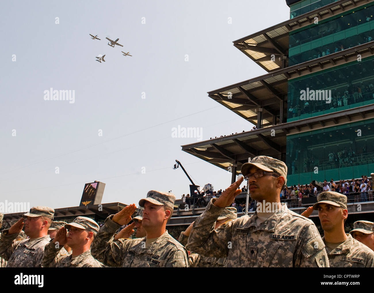 Indiana National Guard troops salute as two P-51 Mustangs, an A-10 Lightning II and an F-16 Fighting Falcon flyover the Indianapolis Motor Speedway just prior to the 96th running of the Indianapolis 500, Sunday, May 27, 2012. Stock Photo