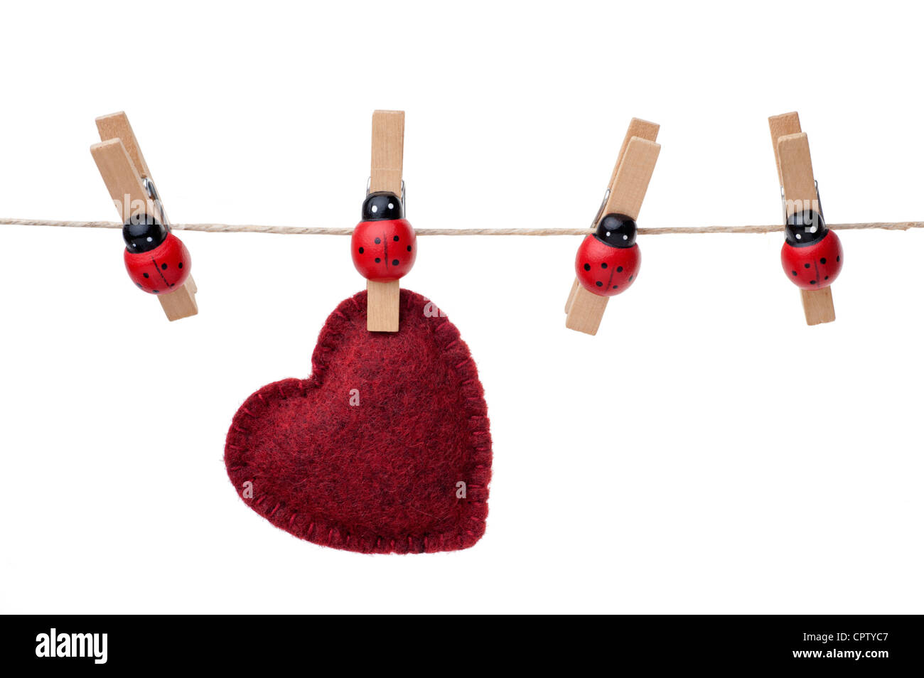 Red heart hanging on a clothesline, four pins, white background Stock Photo