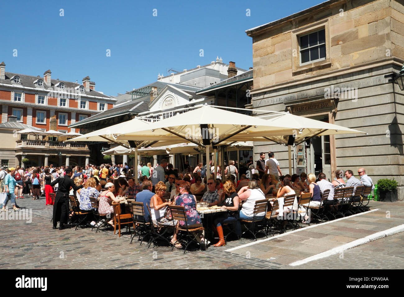Customers at cafe outdoor tables, Covent Garden Piazza, London, UK