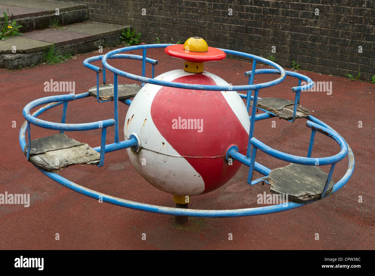 Children's play area roundabout merry-go-round.  Old worn weathered wooden seats that need repairing. Stock Photo