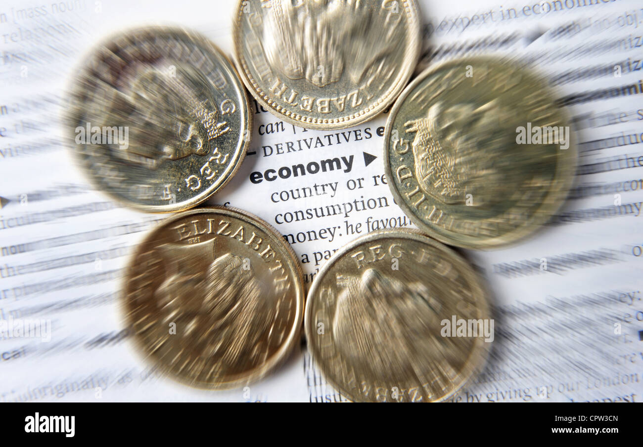 DICTIONARY PAGE WITH THE WORD ECONOMY AND BRITISH POUND COINS RE THE ECONOMY AUSTERITY INCOMES WAGES INTEREST RATES SAVINGS UK Stock Photo