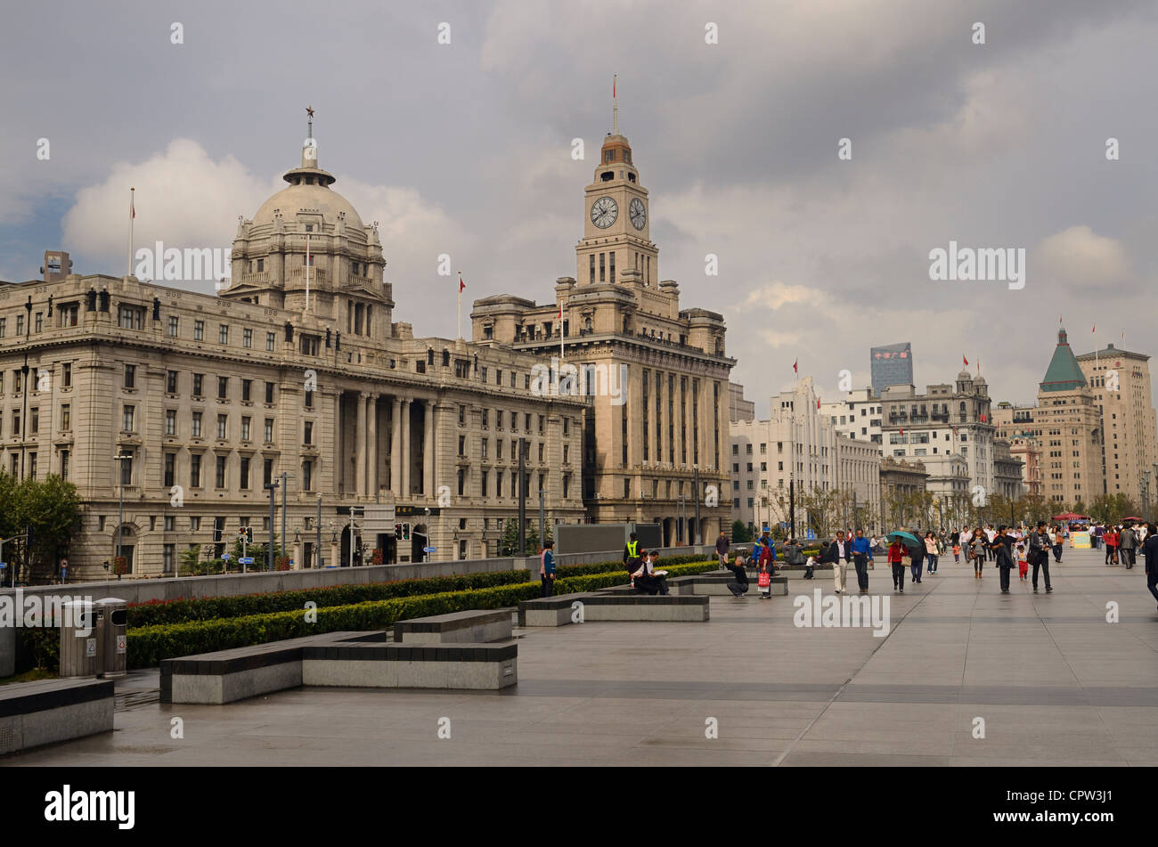 Tourists walking on a wet Bund promenade with old buildings in Shanghai Peoples Republic of China Stock Photo